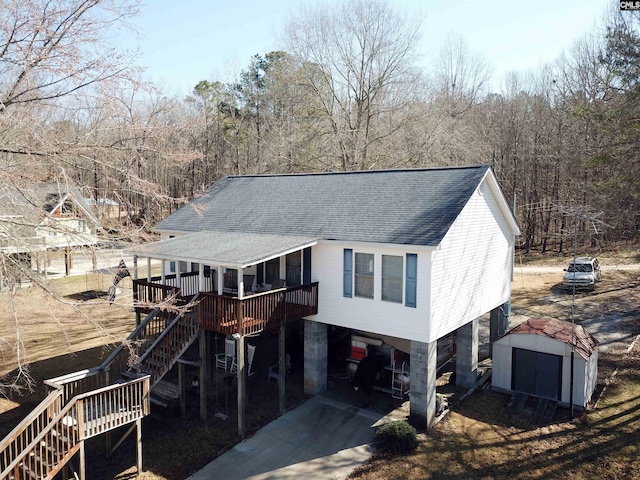 view of front facade with stairway, a storage shed, an outdoor structure, and a shingled roof