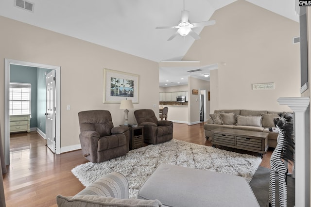 living area with visible vents, high vaulted ceiling, wood finished floors, baseboards, and ceiling fan