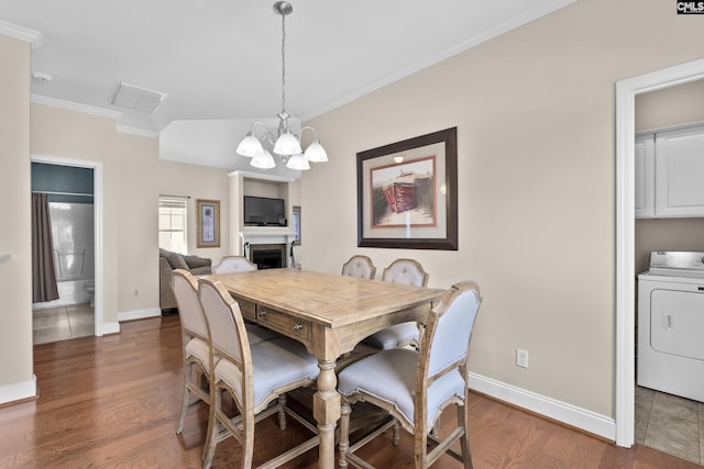 dining area featuring a fireplace, washer / clothes dryer, wood finished floors, and ornamental molding