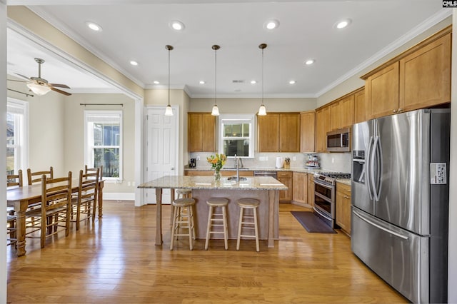 kitchen with brown cabinets, appliances with stainless steel finishes, a breakfast bar area, and a healthy amount of sunlight