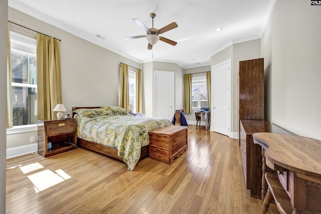 bedroom with visible vents, baseboards, multiple closets, light wood-type flooring, and ornamental molding