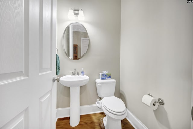 bathroom with a sink, toilet, baseboards, and wood finished floors