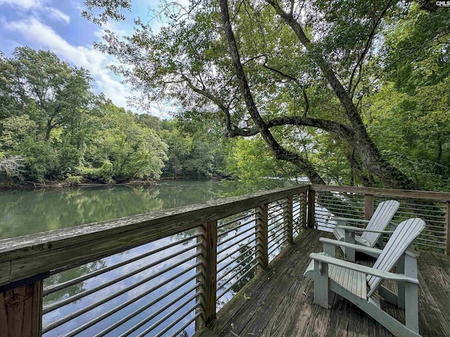 wooden deck featuring a forest view and a water view