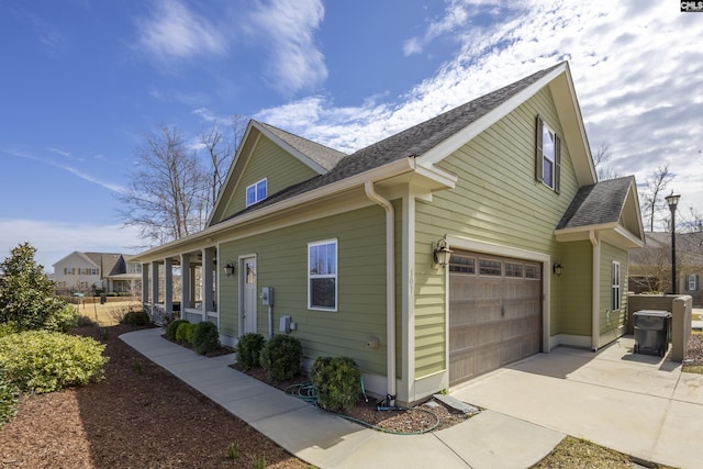 view of property exterior with a garage, concrete driveway, and a shingled roof