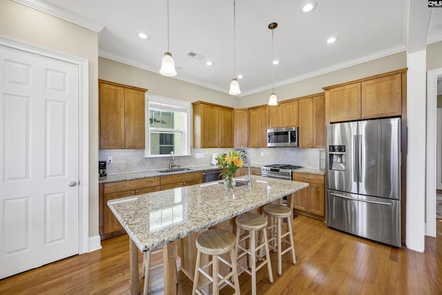 kitchen with brown cabinets, ornamental molding, hardwood / wood-style flooring, a sink, and stainless steel appliances