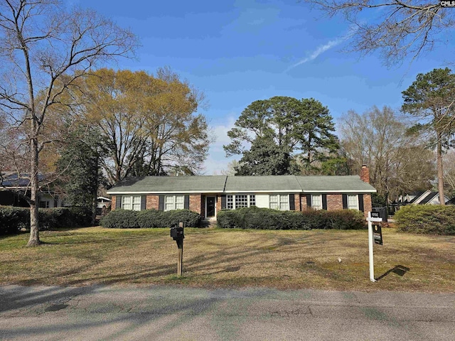 view of front of property with brick siding, a chimney, and a front yard