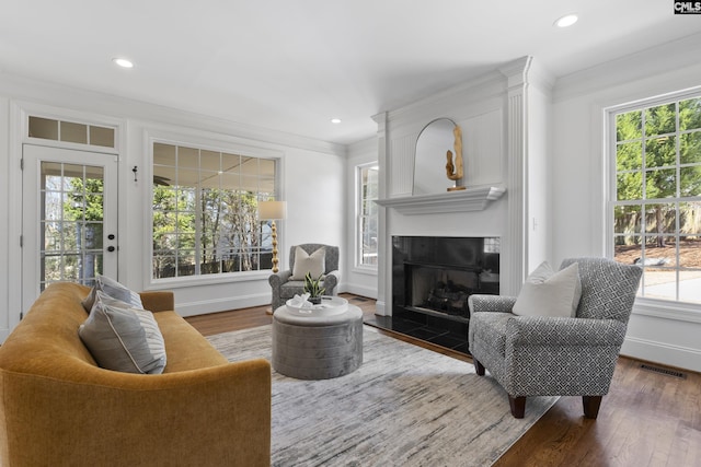 living room featuring visible vents, crown molding, baseboards, a tile fireplace, and wood finished floors