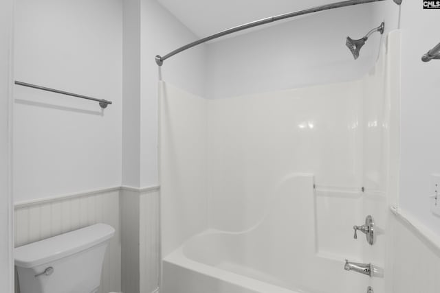 bathroom with shower / washtub combination, toilet, and wainscoting