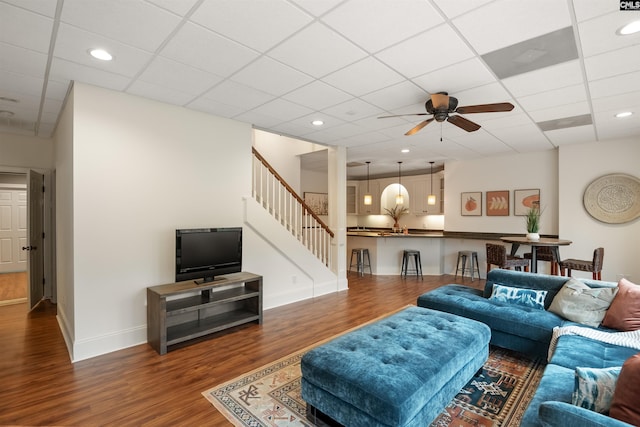 living room with wood finished floors, baseboards, recessed lighting, ceiling fan, and stairs