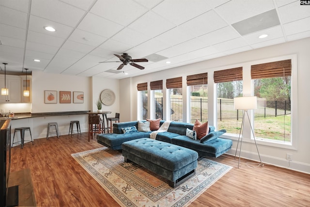 living area featuring recessed lighting, wood finished floors, baseboards, and a paneled ceiling