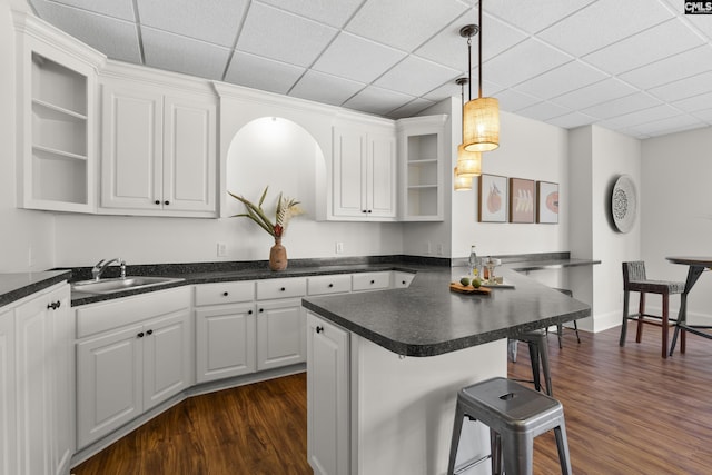 kitchen featuring a sink, white cabinets, a breakfast bar area, and open shelves