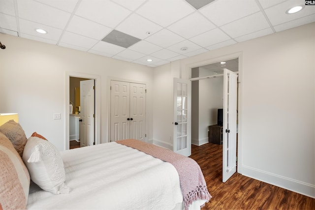 bedroom featuring dark wood-type flooring, a closet, baseboards, and a drop ceiling