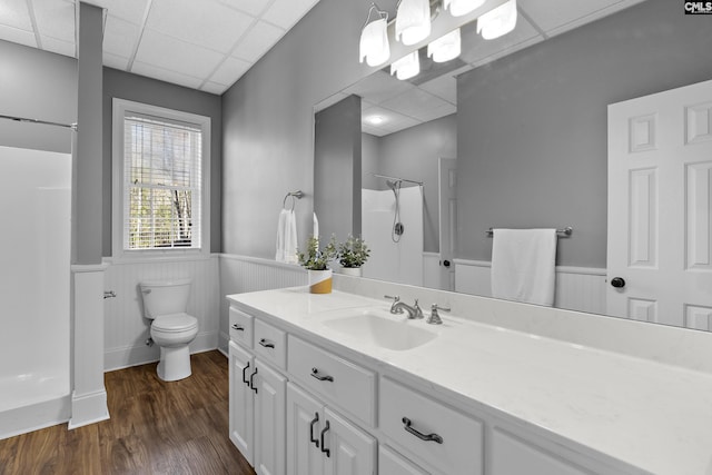 bathroom with walk in shower, a drop ceiling, toilet, wainscoting, and wood finished floors