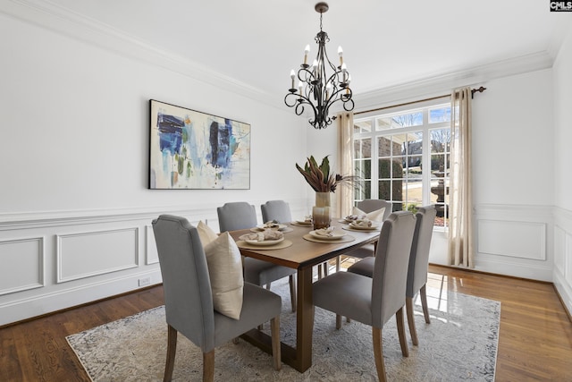 dining area with crown molding, wood finished floors, wainscoting, and a chandelier