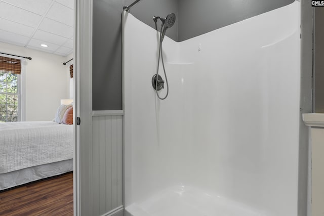 ensuite bathroom featuring a drop ceiling, wood finished floors, recessed lighting, connected bathroom, and a shower