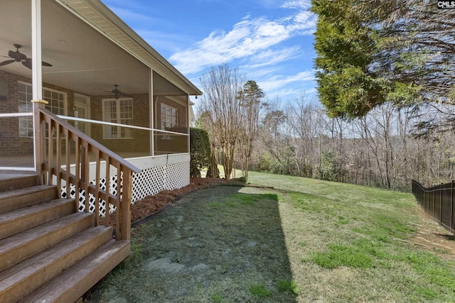 view of yard with fence, ceiling fan, and a sunroom