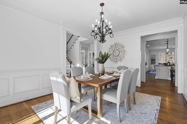 dining room featuring stairway, a decorative wall, a chandelier, and ornamental molding