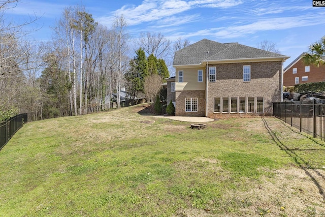 rear view of house featuring a yard, a patio, brick siding, and a fenced backyard