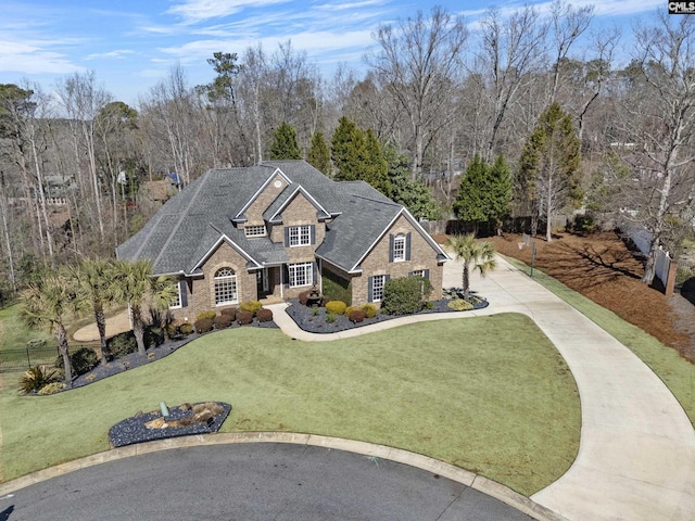 traditional-style home featuring a front lawn, driveway, and roof with shingles