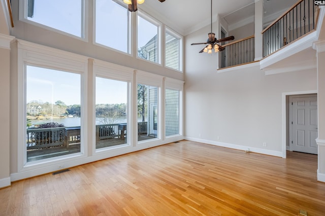 unfurnished living room with baseboards, visible vents, ornamental molding, ceiling fan, and light wood-style floors