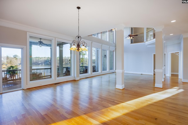 unfurnished dining area with crown molding, light wood finished floors, baseboards, and ornate columns