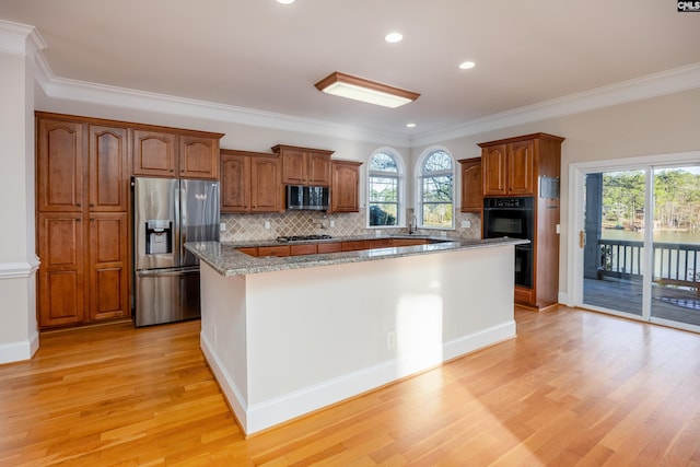 kitchen with a sink, a center island, light wood-style floors, appliances with stainless steel finishes, and a healthy amount of sunlight