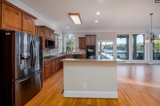 kitchen with tasteful backsplash, appliances with stainless steel finishes, crown molding, light wood finished floors, and hanging light fixtures