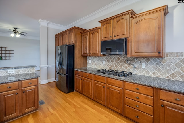 kitchen with stainless steel appliances, visible vents, brown cabinetry, and decorative columns