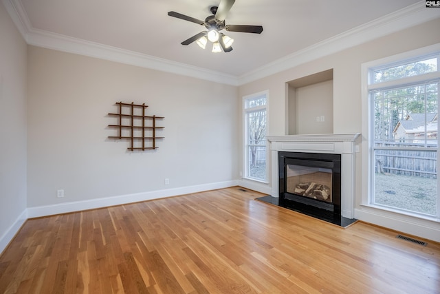 unfurnished living room with baseboards, a healthy amount of sunlight, a glass covered fireplace, and light wood finished floors