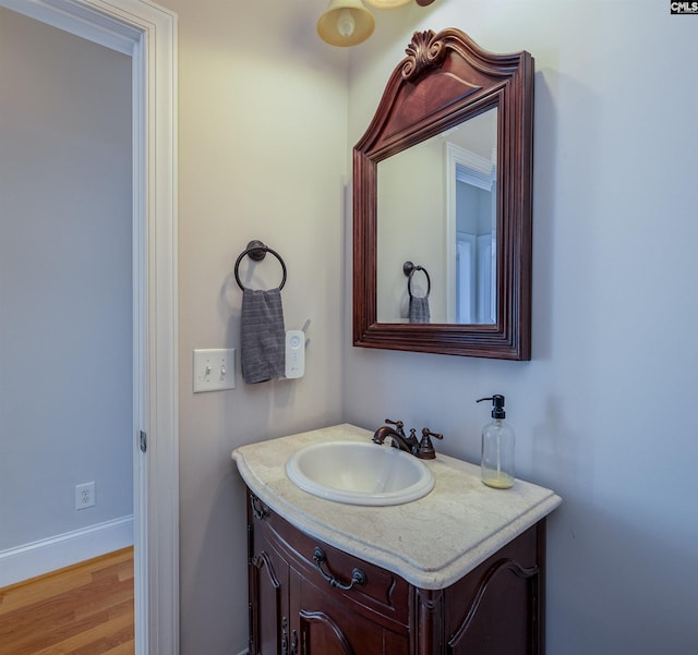 bathroom with baseboards, wood finished floors, and vanity