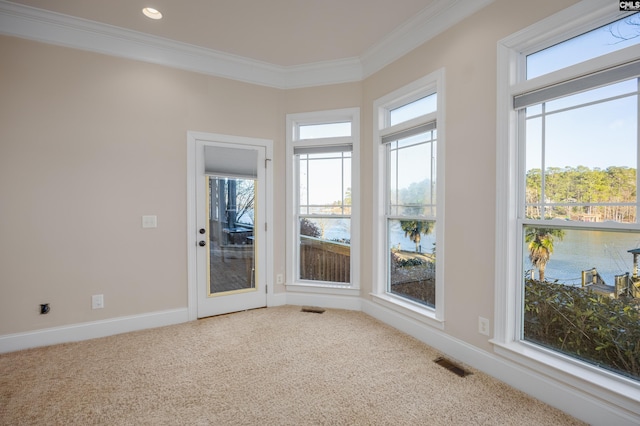 carpeted spare room with a wealth of natural light, visible vents, and crown molding