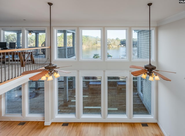 unfurnished sunroom featuring visible vents, a ceiling fan, and a water view