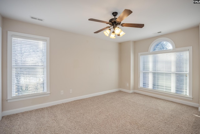 empty room with a wealth of natural light, visible vents, and ceiling fan