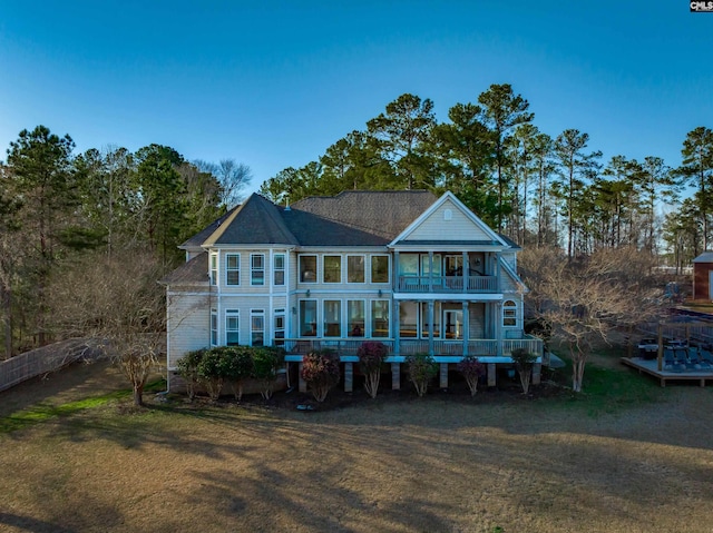 back of house featuring a balcony and a yard