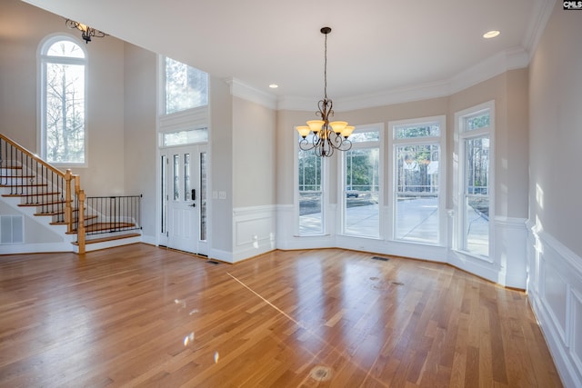 entrance foyer with a chandelier, stairway, plenty of natural light, and light wood-style floors