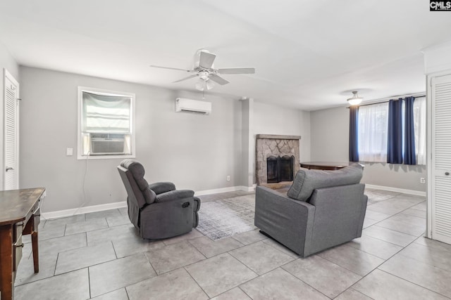 living area with baseboards, ceiling fan, a wall mounted air conditioner, a stone fireplace, and cooling unit