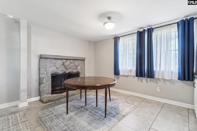 interior space featuring light tile patterned floors, a fireplace, and baseboards