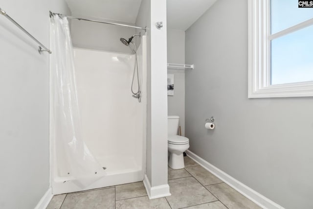 bathroom with tile patterned floors, toilet, and a shower stall