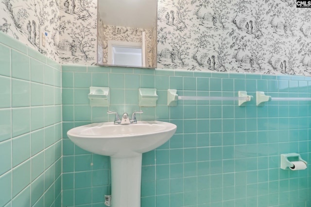 bathroom featuring a wainscoted wall and wallpapered walls