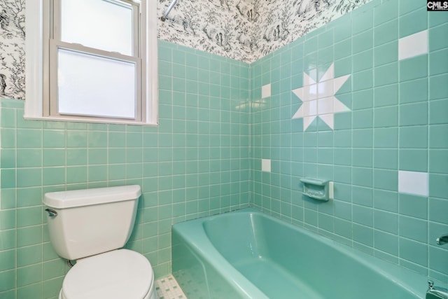 bathroom with wainscoting, toilet, wallpapered walls, and tile walls