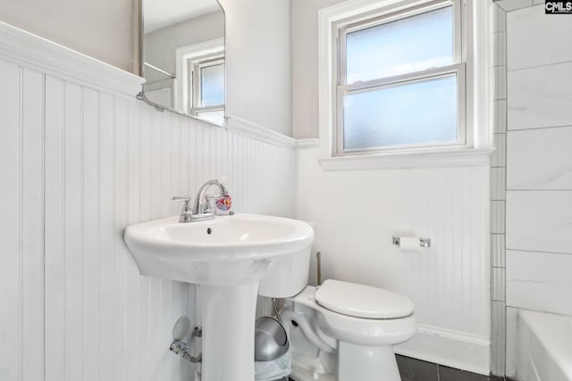 bathroom with plenty of natural light, toilet, and a wainscoted wall