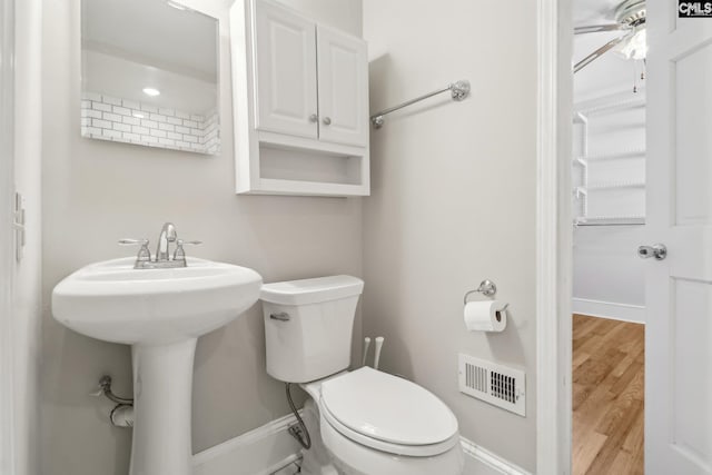 bathroom with visible vents, toilet, wood finished floors, baseboards, and ceiling fan