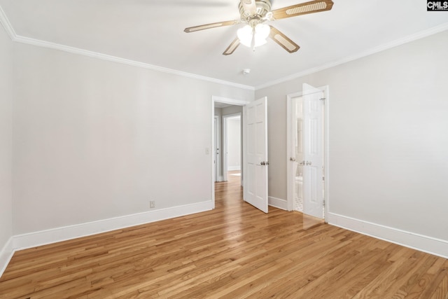 spare room featuring light wood finished floors, crown molding, and baseboards