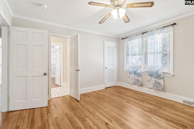 unfurnished bedroom with light wood finished floors, visible vents, crown molding, baseboards, and a closet