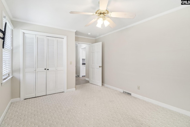 unfurnished bedroom with carpet flooring, visible vents, baseboards, and ornamental molding