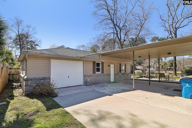 view of front of house featuring stone siding, fence, a garage, and driveway