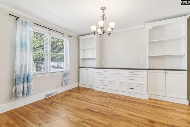 unfurnished dining area with visible vents, light wood-style floors, ornamental molding, and a chandelier