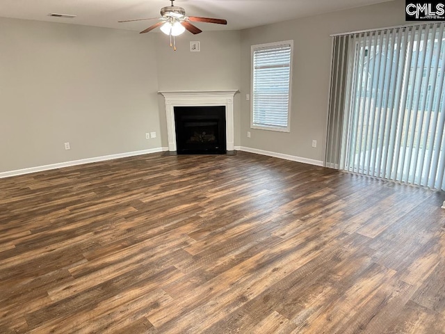 unfurnished living room with visible vents, baseboards, dark wood finished floors, and a ceiling fan