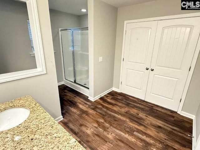 full bath featuring baseboards, wood finished floors, a stall shower, and vanity