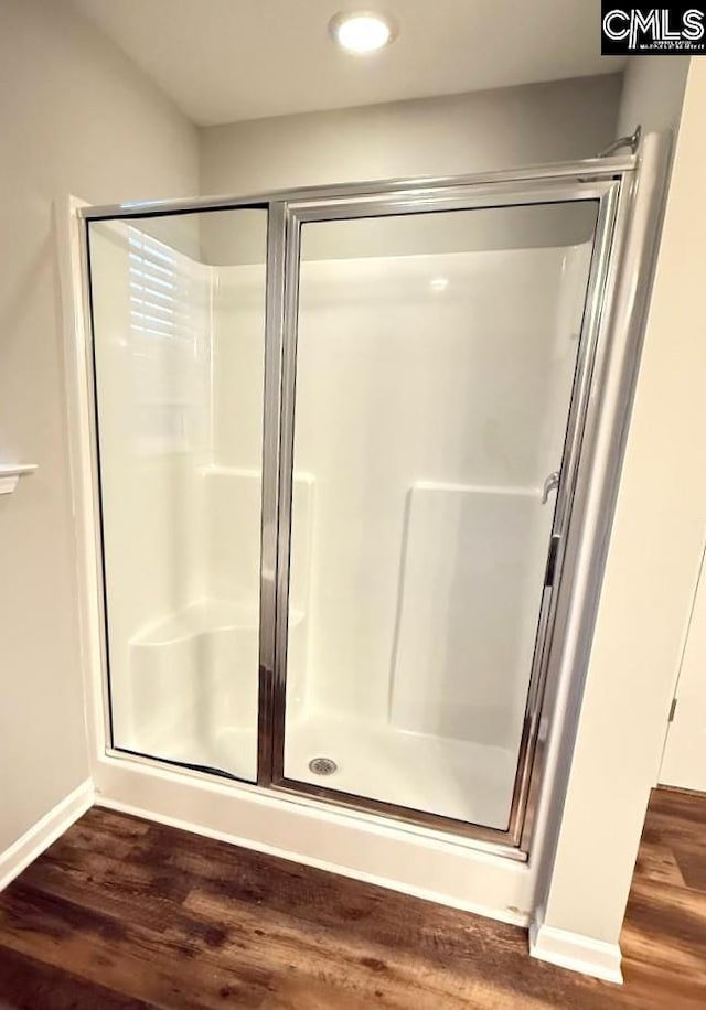 bathroom with a shower stall, wood finished floors, and baseboards